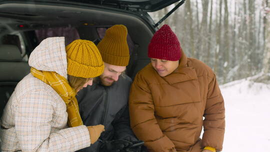 下雪天朋友们坐在汽车后备箱里聊天