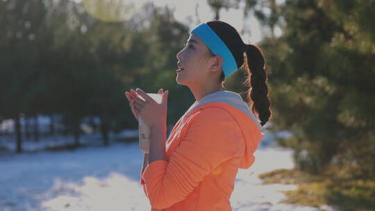 青年女人在雪地里喝热水