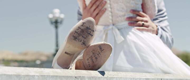 新郎新娘在户外相拥的墙上挂着签名的婚鞋
