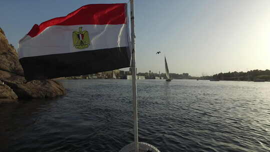 有国旗的船行驶在日落的河面上