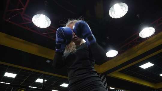 一个美丽年轻活跃的女人在拳击场训练，她练