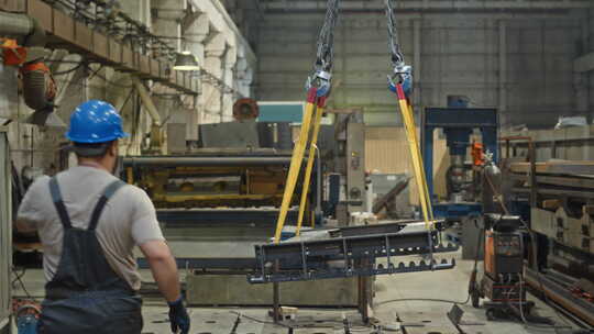 工厂工人从起重机上的起重皮带上取下沉重的