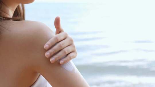 年轻女性海边涂抹防晒霜视频素材模板下载