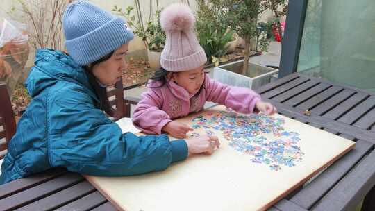 母女在别墅院子木桌子上玩拼图游戏