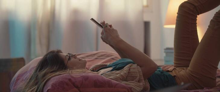 女人躺在床上玩手机