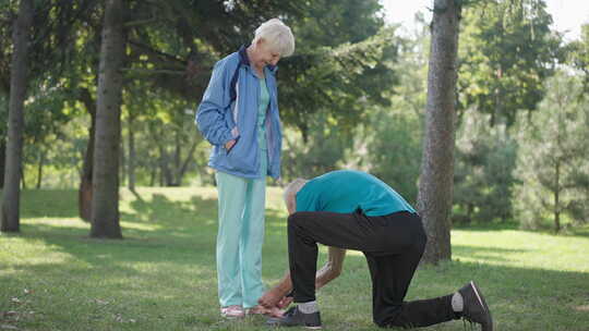 感恩的老年妻子拥抱丈夫在春夏公园的运动鞋