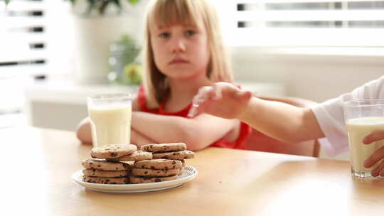 兄弟姐妹在餐桌上分享吃饼干和喝牛奶的快乐