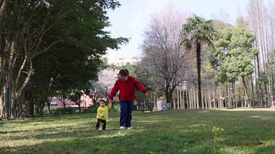 小女孩和妈妈在阳光晴朗的春天公园玩耍