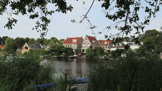 荷兰小艇通过河边村庄视频素材模板下载