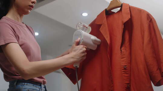亚洲女人在橙色衬衫上使用蒸笼