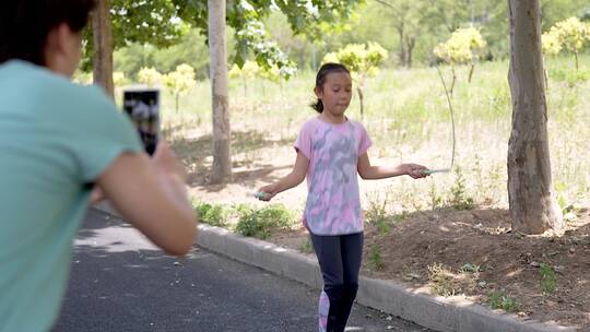 用手机记录拍摄女儿跳绳的母亲