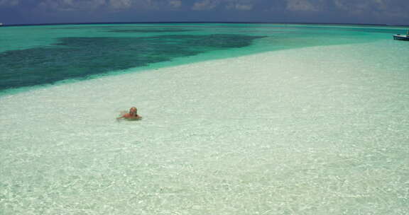 一个女人躺在荒岛海滩上的水中，穿着明亮的