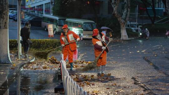 清晨慢镜头记录环卫工人打扫雨后落叶的街道