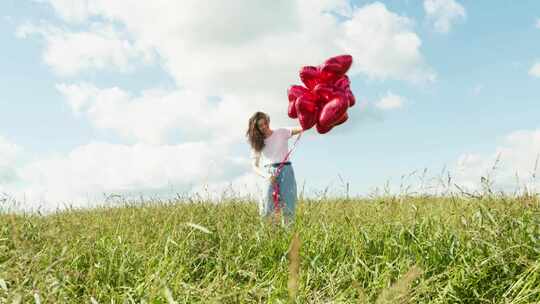 女人在草地上手拿红色爱心气球 唯美浪漫