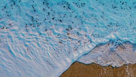 海洋波浪泡沫拍打在沙滩上