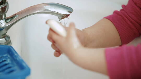 女孩在水龙头下用肥皂洗手
