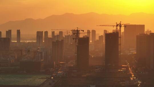 夕阳下建设开发中的城市建筑工地塔吊剪影