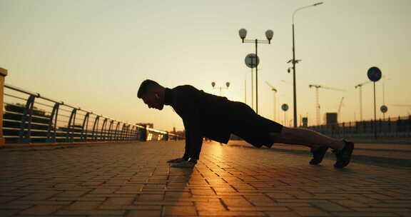 日落时分，年轻运动员在城市街道上做俯卧撑