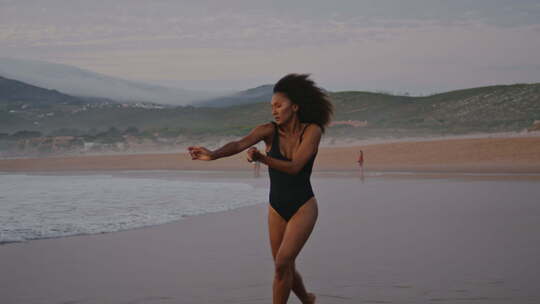 阴郁天空中跳舞的现代海滩女人