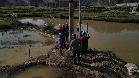 航拍水田里面安装电线杆