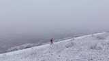航拍男子走在新疆禾木村的风雪中高清在线视频素材下载