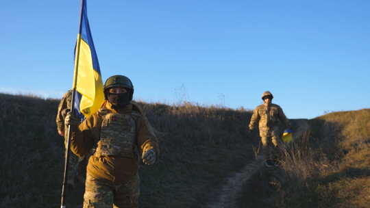 乌克兰军队士兵举着乌克兰国旗在战场上行走