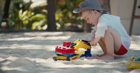 孩子在海滩沙滩上玩塑料车