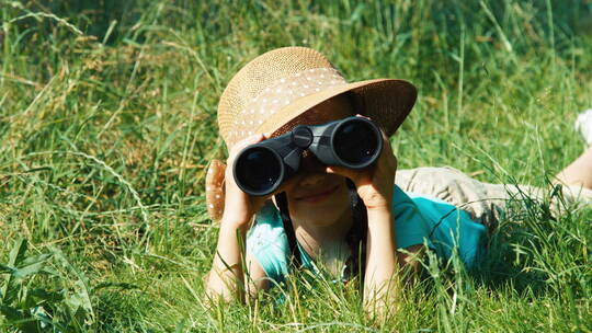 女孩趴在草丛里用望远镜