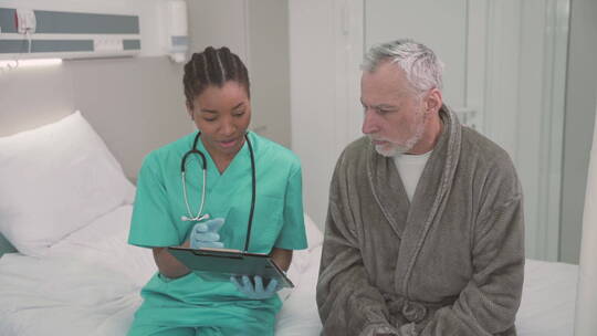 医生和一位老病人坐在病床边上