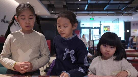 在餐厅翻阅菜单点餐的三个亚洲女孩