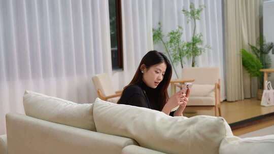 室内女子坐沙发玩手机画面