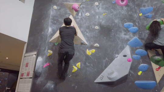 亚洲登山者家伙在健身馆爬上户外抱石墙。