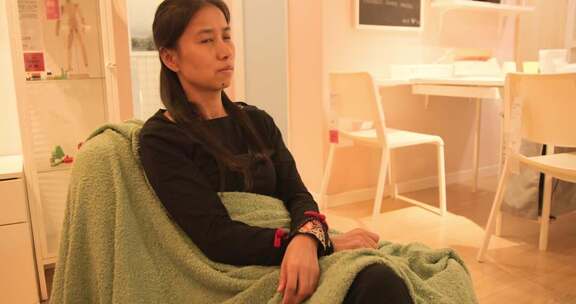 室内坐着盖毯子的女性