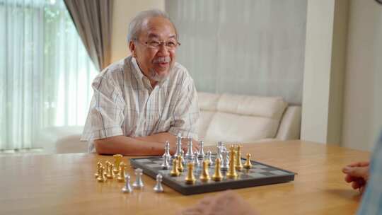 亚洲老年男性和朋友一起下棋，在家享受退休生活。视频素材模板下载