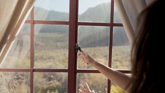 女人用手推开窗看屋外的风景