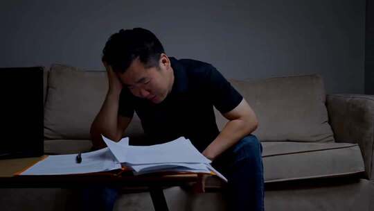 男人沙发前伏案处理文件