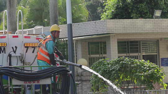 环卫工操作洒水车进行街道喷灌作业