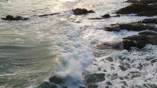 航拍夕阳下的波涛汹涌的海浪冲向岸边