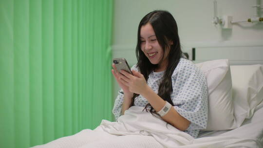 病人躺在病床上开心的玩手机