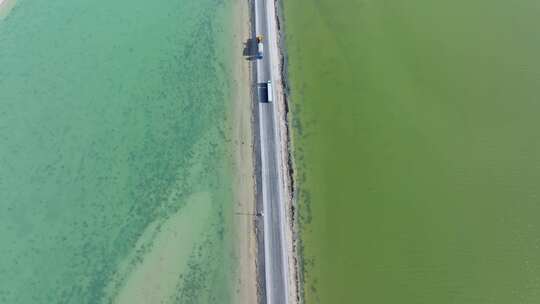 航拍货车行驶在青海西台吉乃尔湖中的公路上