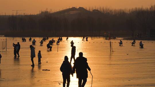 夕阳下冰面滑冰的游客人群