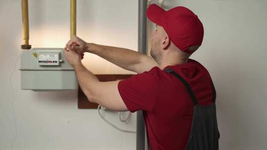 红帽技术员在室内检查和维护住宅燃气表视频素材模板下载