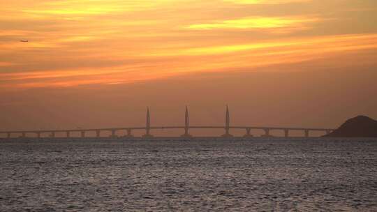 飞机和海鸥飞过朝霞中的港珠澳大桥海豚塔