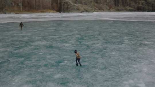 吉泽尔山谷冰冻的哈尔蒂湖上人们滑冰剪影的鸟瞰图。圆圈