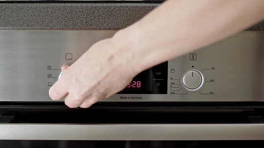 厨师或家庭主妇启动烤箱并将温度设置为180摄氏度