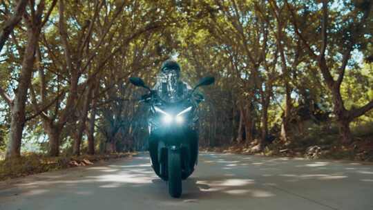 摩托车行驶在斑驳阳光下的林间小路