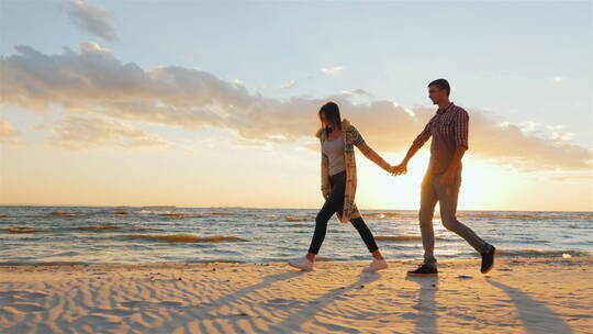 情侣在日落在的海滩上散步