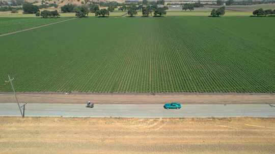 无人机拍摄的浅蓝色经典芥末在加州乡村公路上行驶的镜头