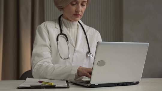 女医生在诊所办公室的笔记本电脑上查看患者