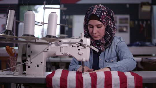 戴头巾缝制美国国旗的女人